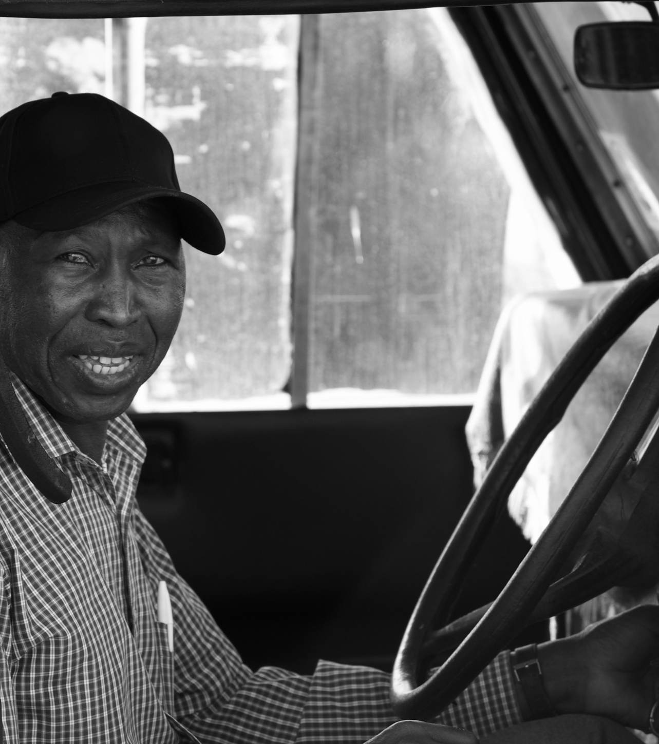 Black and white photo of Andrew smiling from the driver's seat of a vehicle