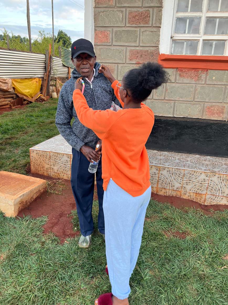 A family member adjusting the collar of Andrew's jacket outside the family home