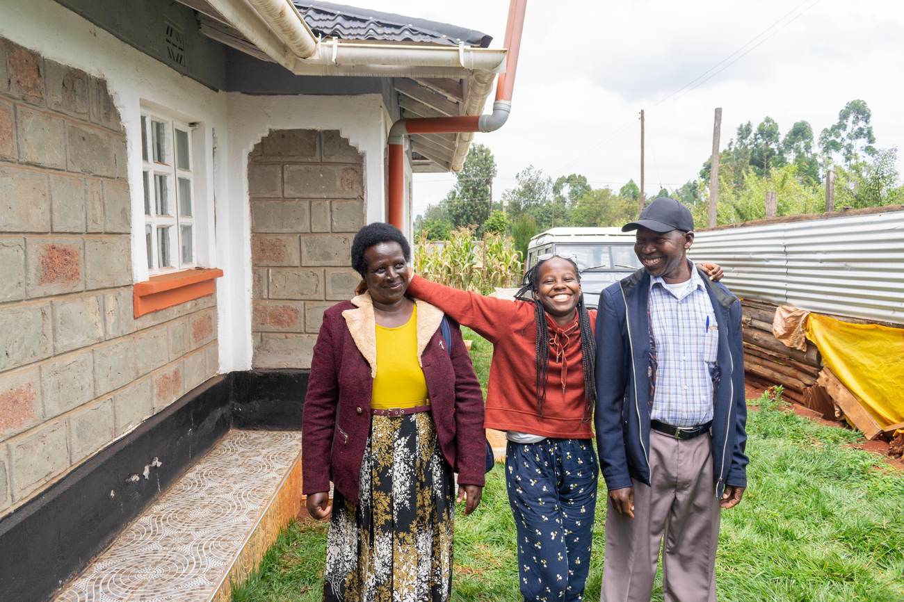 Andrew standing with two family members outside the family home, all smiling