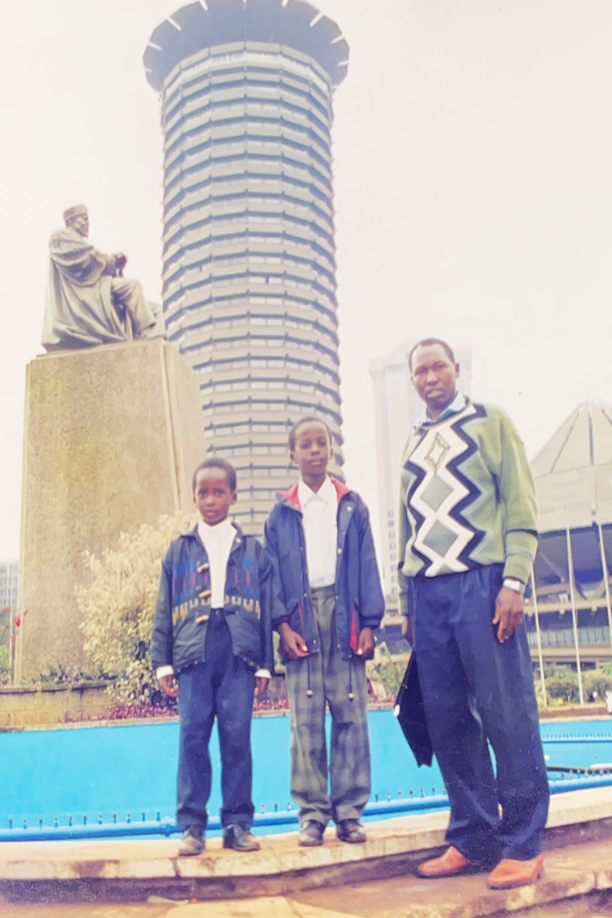 Andrew with two children beside the Jomo Kenyatta statue in Nairobi.