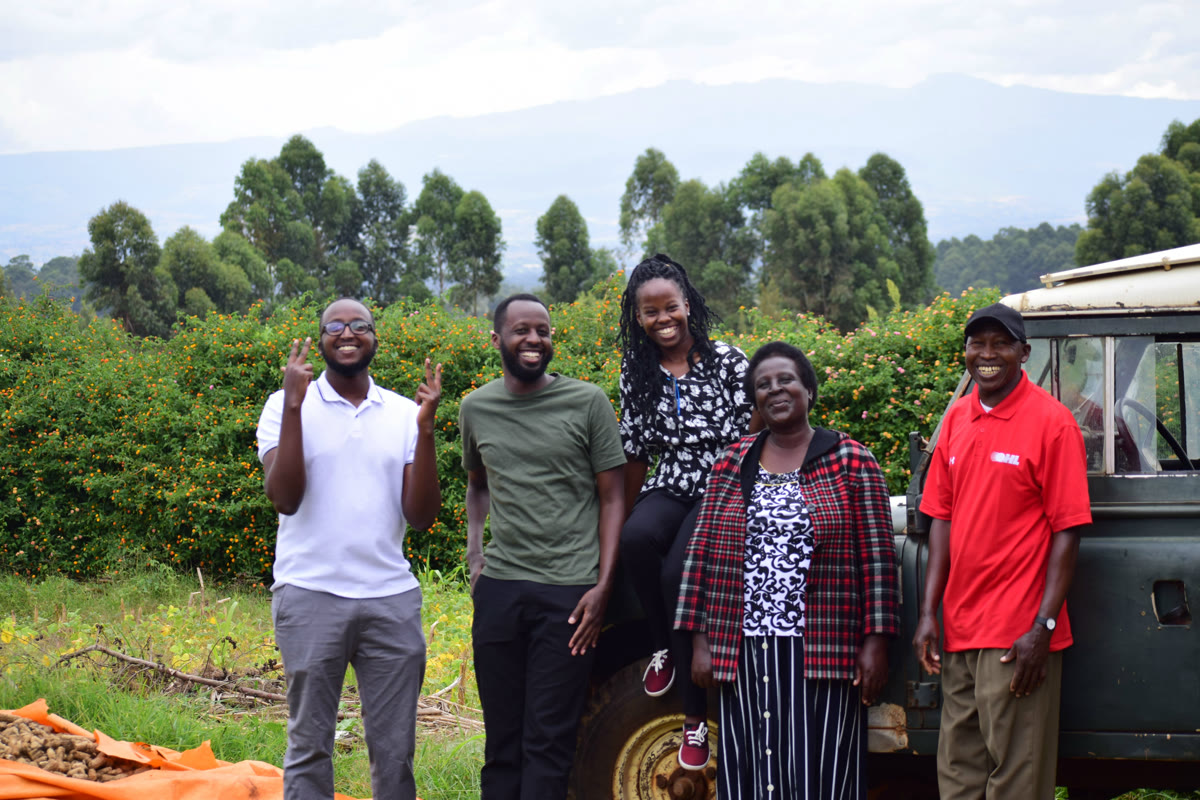 Five family members smiling outdoors beside a vehicle.