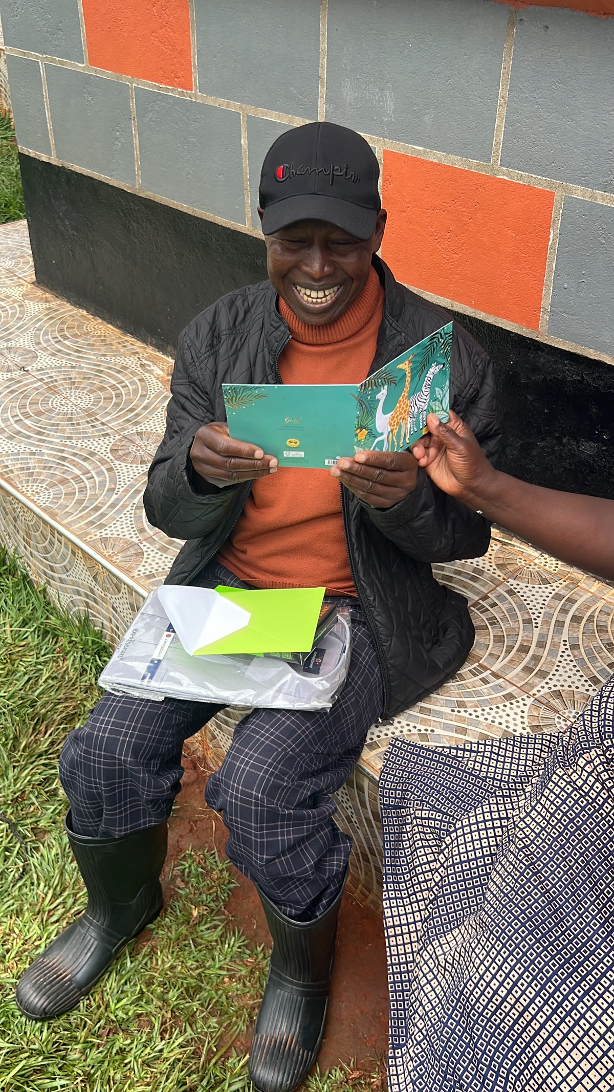 Andrew smiling while reading a greeting card, seated outdoors.