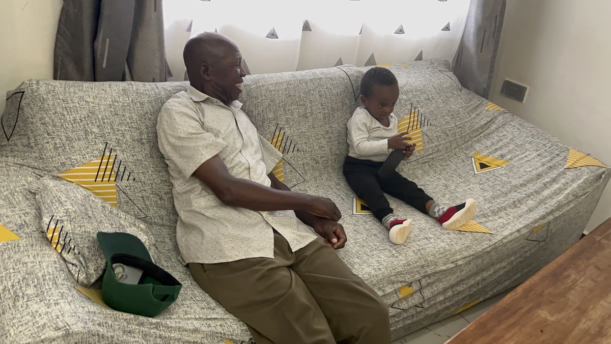 Andrew seated on a sofa beside a young child.