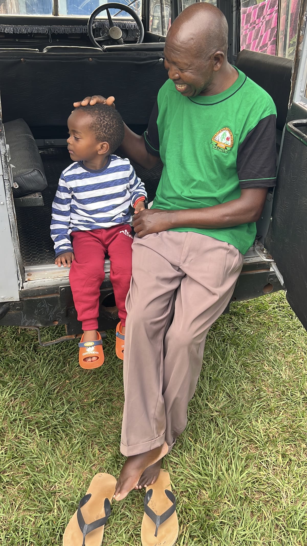 Andrew seated beside a young child in the doorway of a vehicle.
